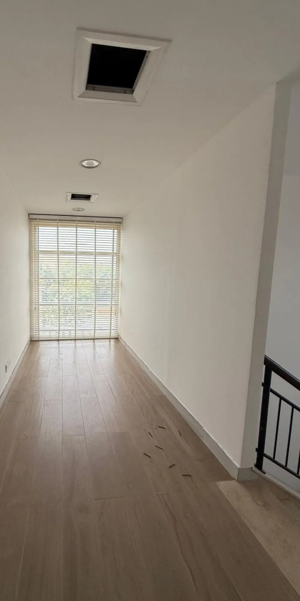 Before: long empty upstairs corridor with wood-look floor and window blinds