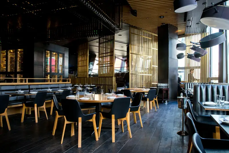 Restaurant interior with timber slats and dark dining chairs