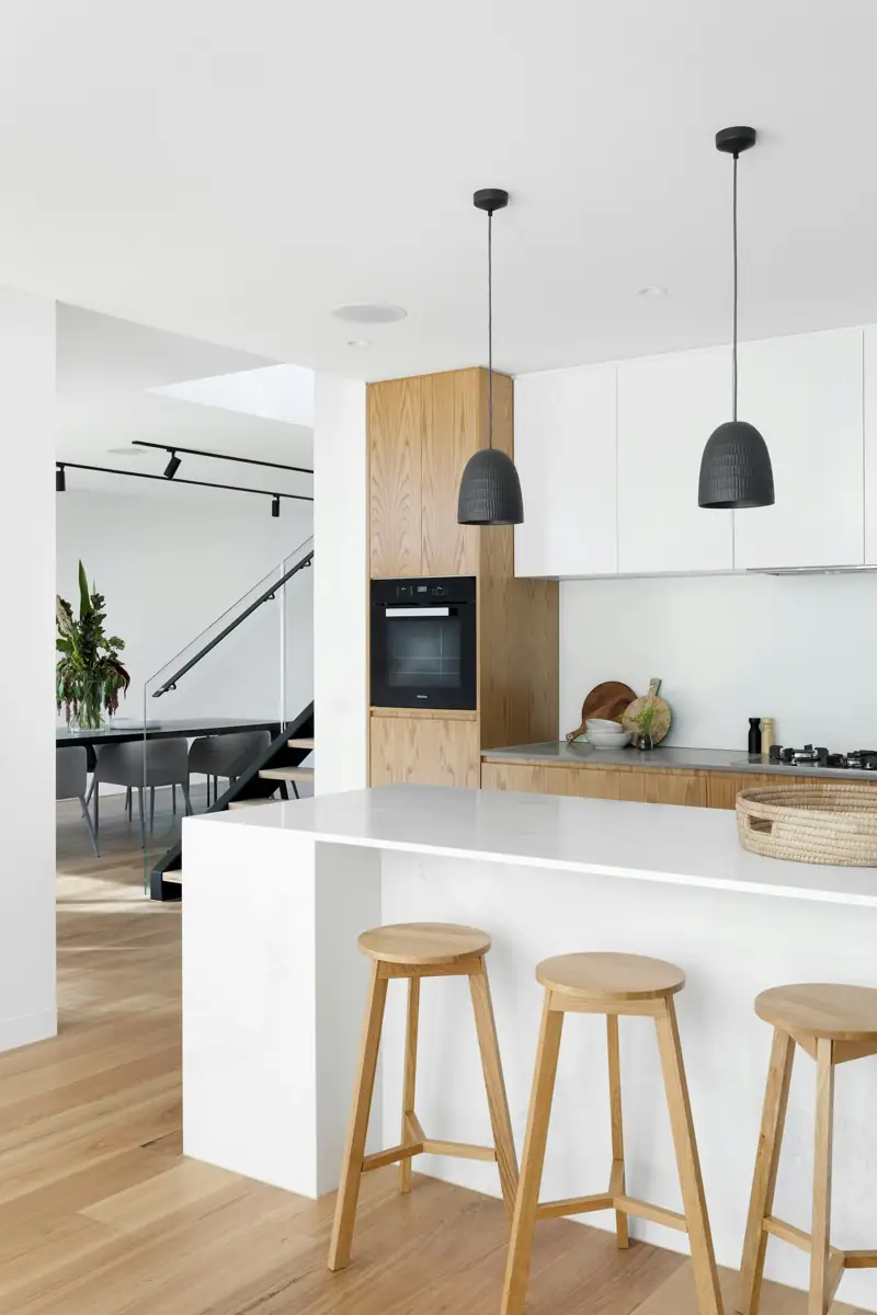 Modern white kitchen with oak cabinets, an island and bar stools